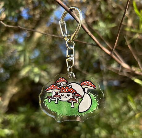 An acrylic keychain with double sided printing of character 'Amanita'